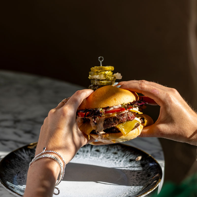 Justin Vaiciunas, Head Chef of The Jackson A woman holding a burger